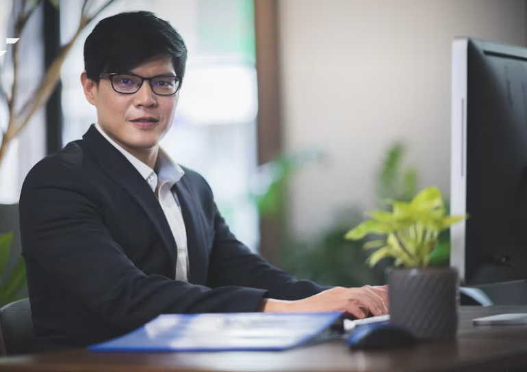 Женщина, менеджер по перевозкам, сидит за столом в офисе, зелёный пиджак